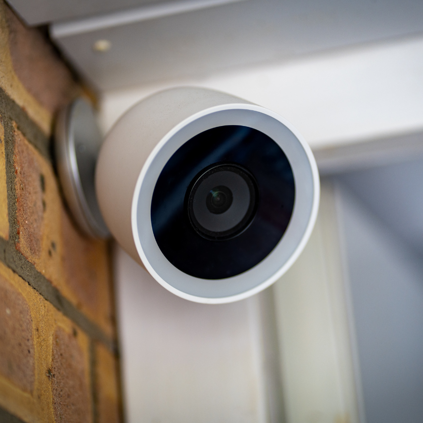 a white security camera on the brick wall of a house